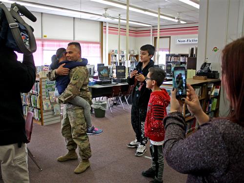 Soldier hugs daughter as family looks on 