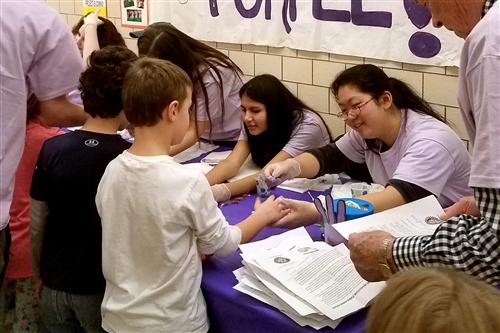 Students have their pinkies painted purple 