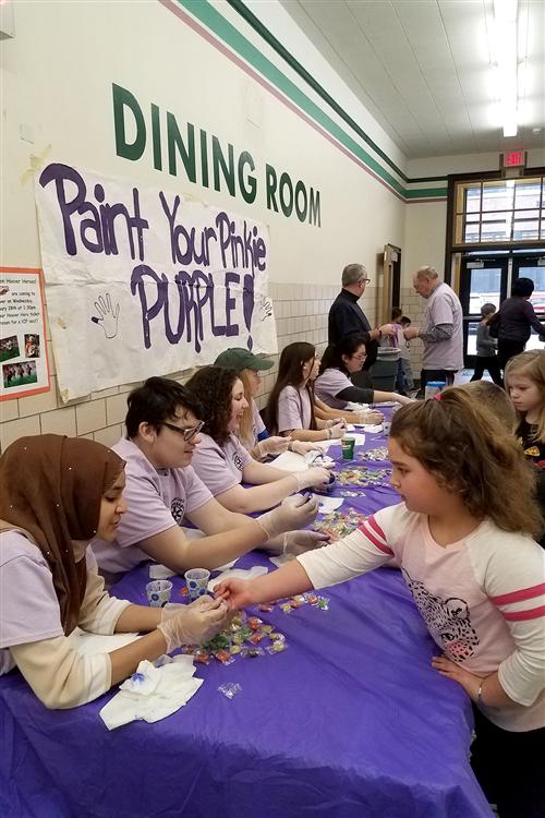 Students have their pinkies painted purple 