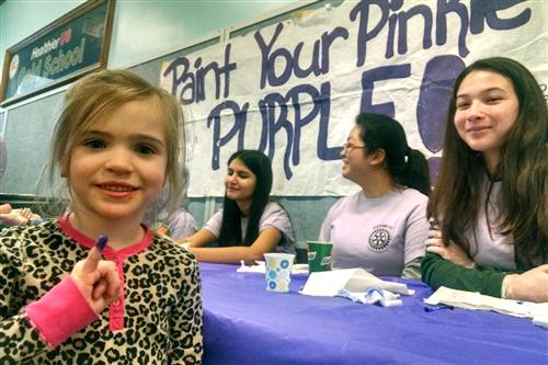 Students have their pinkies painted purple 