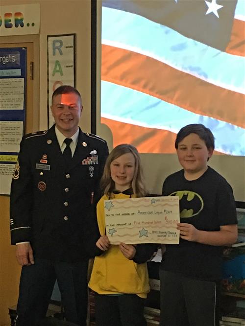 Students Emma Piadlo and William Nowak presenting First Sergeant Trudeau  