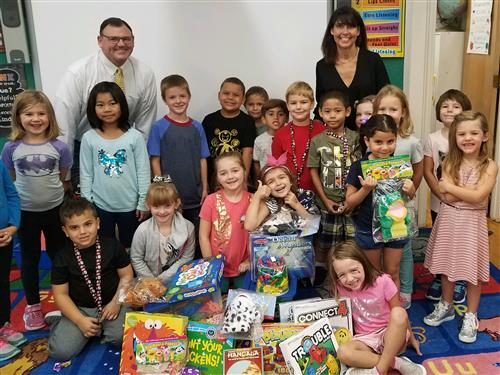 Teacher Katie Sacco & Principal David King pose with students and games/activities 