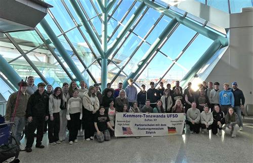 students pose in the airport after welcoming students from Germany