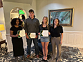  students and a counselor pose in a room with scholarship certificates