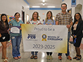  staff members hold up a banner honoring the school's PTA
