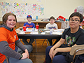  Students smile at a table while enjoying a pizza party for being a top reader.
