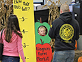  child puts head through a photo hole at a harvest festival