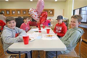 students smile at a table while enjoying a pizza party