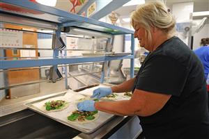 staff member puts vegetables on mini pizzas