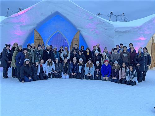 students post in front of an ice castle