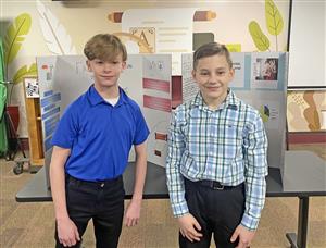 two students stand in front of their projects