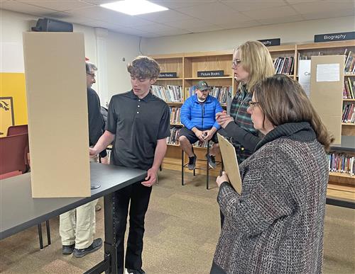 Student presents in front of two teachers