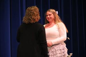student smiles and shakes hand with teacher on stage