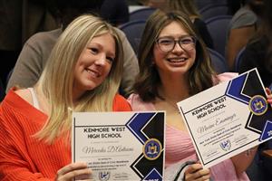 two students hold up certificate awards