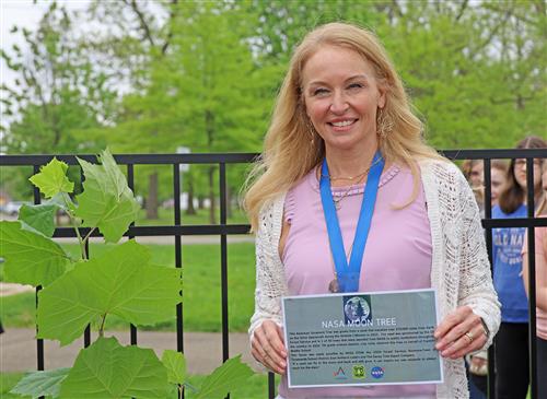 Franklin teacher smiles with a NASA Moon Tree certificate