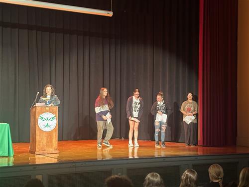 students stand on stage with awards