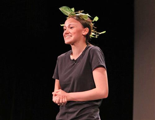 Kenmore West student poses on stage dressed in all black with a wreath on her head