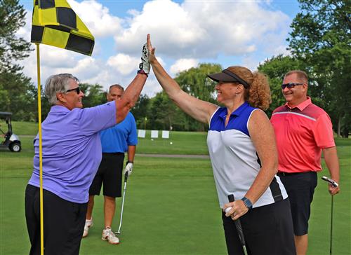 Two golfers high five after a putt