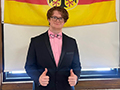 student stands in front of the German flag with thumbs up