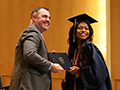  student smiles with diploma alongside principal