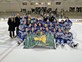  girls hockey team sits on ice posing with championship banner