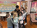  upper and lower level students hug in a classroom