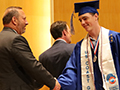  student smiles as he shakes superintendent's hand at graduation