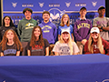 student athletes pose in their collegiate shirts after signing their letters of intent
