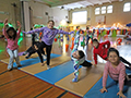  students do yoga poses on the gym floor in PE class
