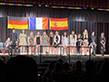  World Language students stand on stage with honors cords around their neck at a special ceremony.