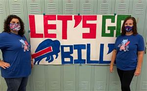 Two teachers standing in front of a let's go bills sign